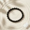 Black tourmaline 8mm crystal bracelet with polished round beads on textured neutral background