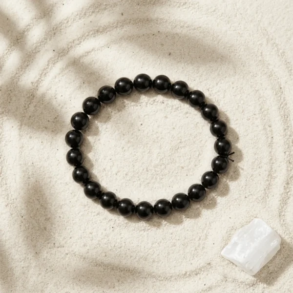 Black tourmaline 8mm crystal bracelet with polished round beads on textured neutral background