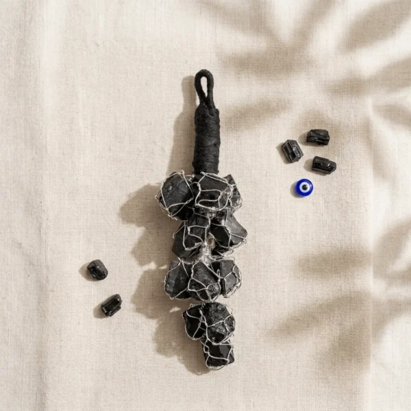 Black Tourmaline crystal hanger styled with raw Black Tourmaline stones and an evil eye charm