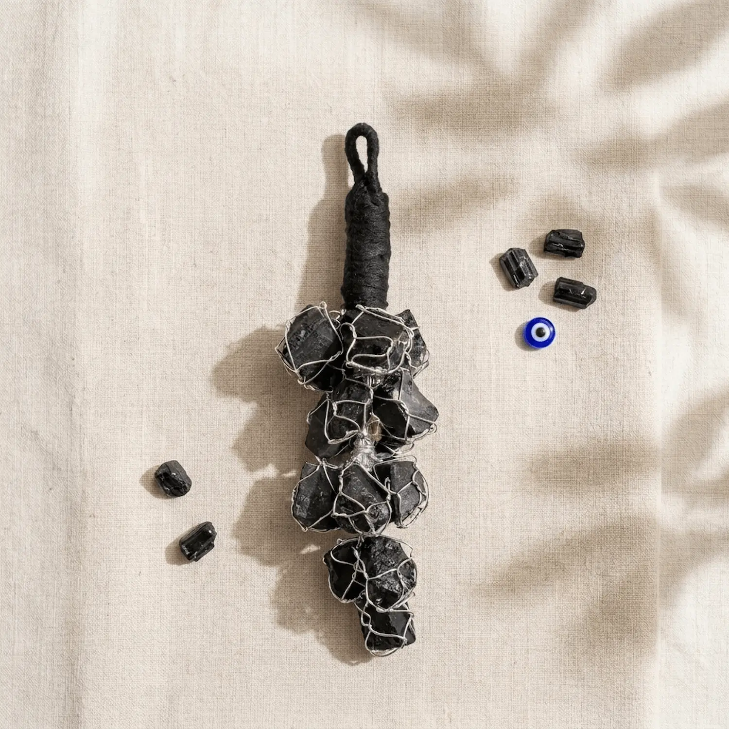 Black Tourmaline crystal hanger styled with raw Black Tourmaline stones and an evil eye charm