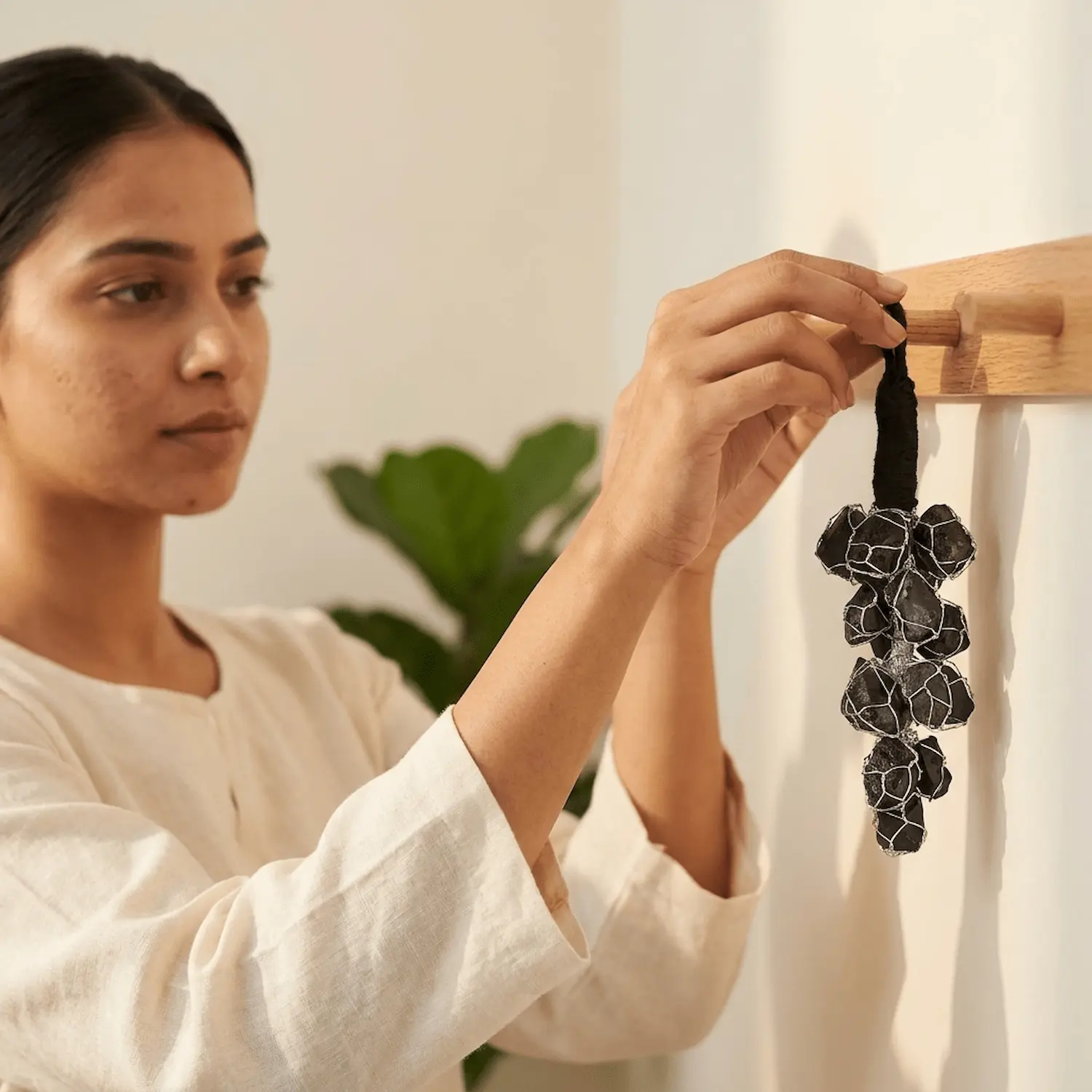 Black Tourmaline crystal hanger being placed on a wall hook