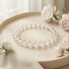 Clear quartz bracelet 8mm styled on neutral plate with soft floral aesthetics