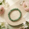 Green aventurine bracelet styled with soft decor and natural elements
