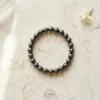 Natural Hematite crystal bracelet 8mm displayed on light textured stone surface