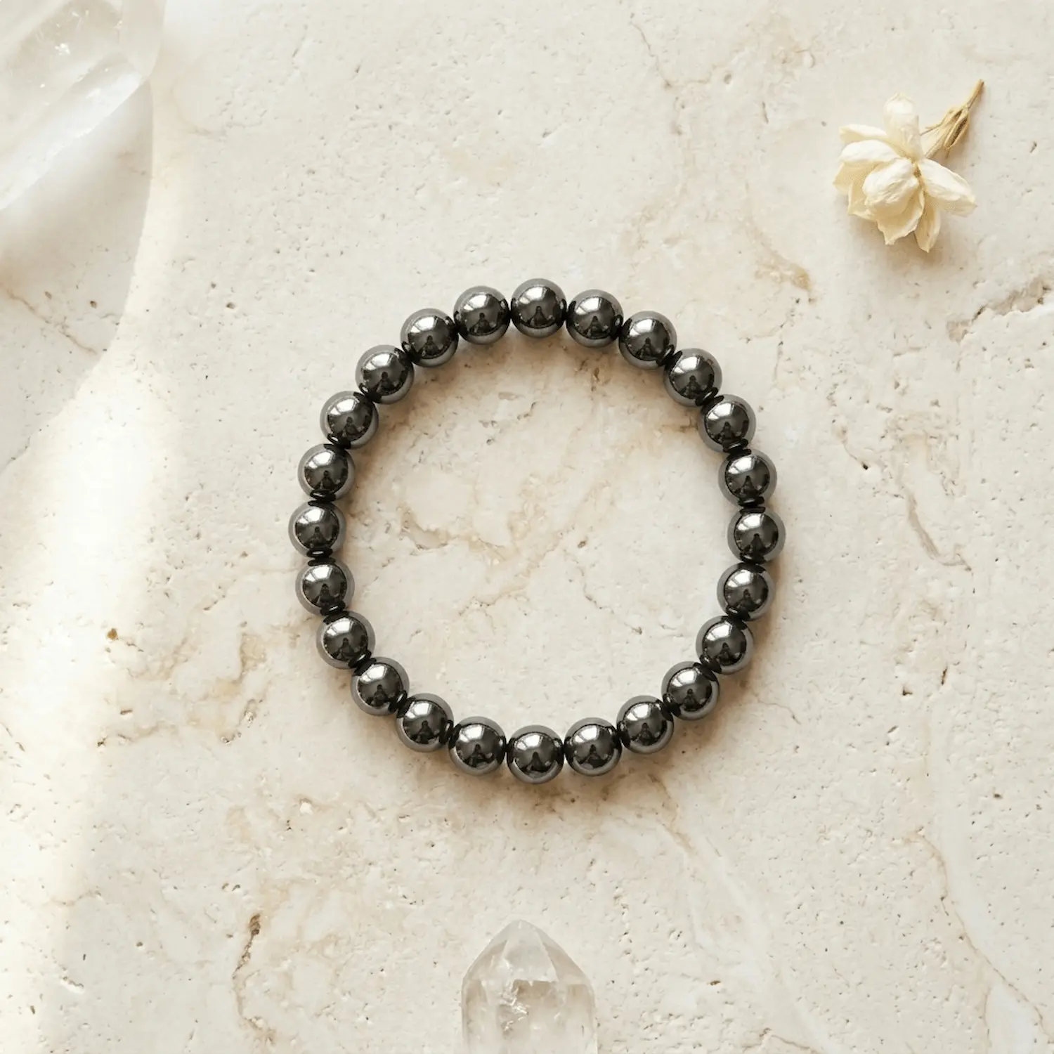Natural Hematite crystal bracelet 8mm displayed on light textured stone surface