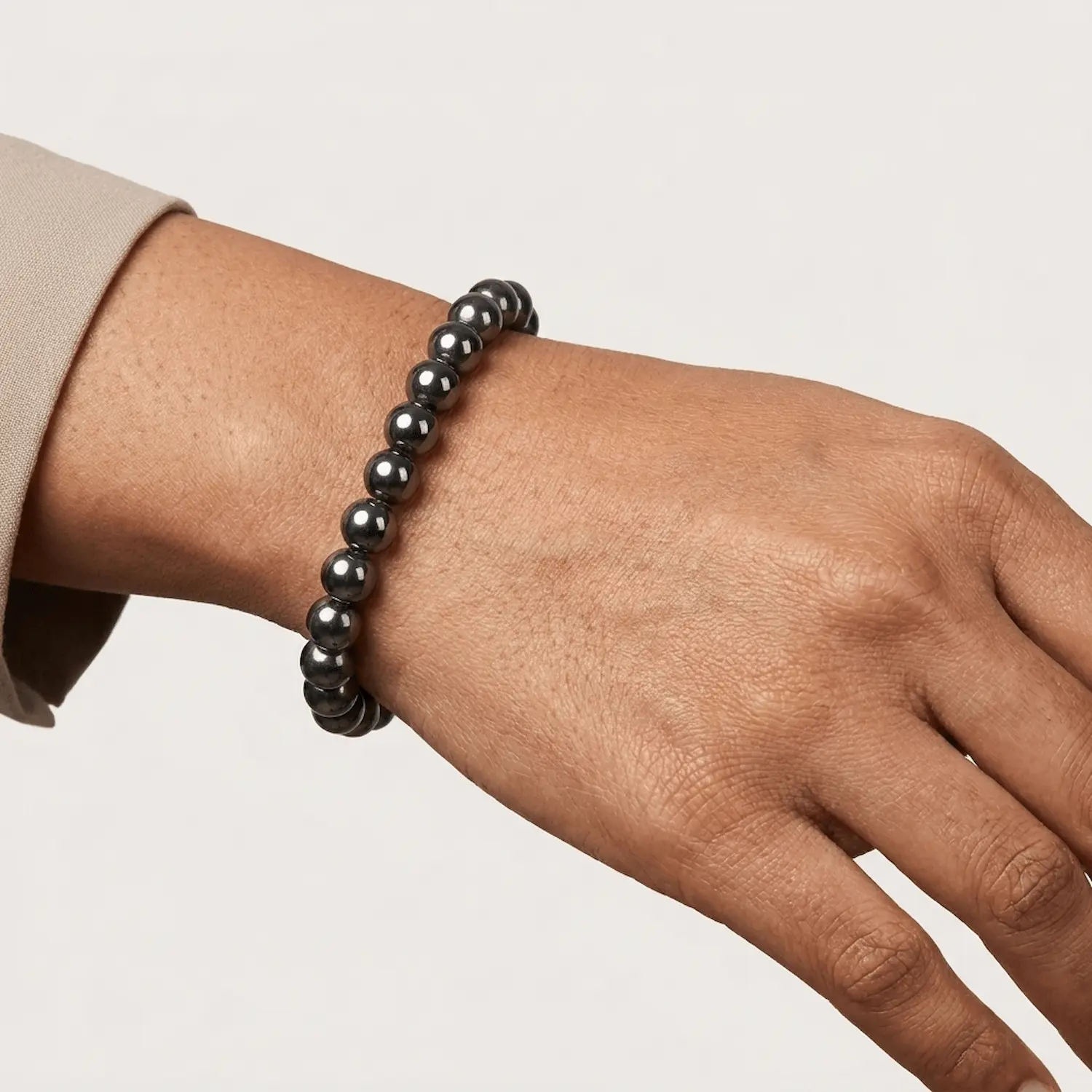 Close-up wrist shot of Hematite 8mm crystal bracelet with minimal beige background