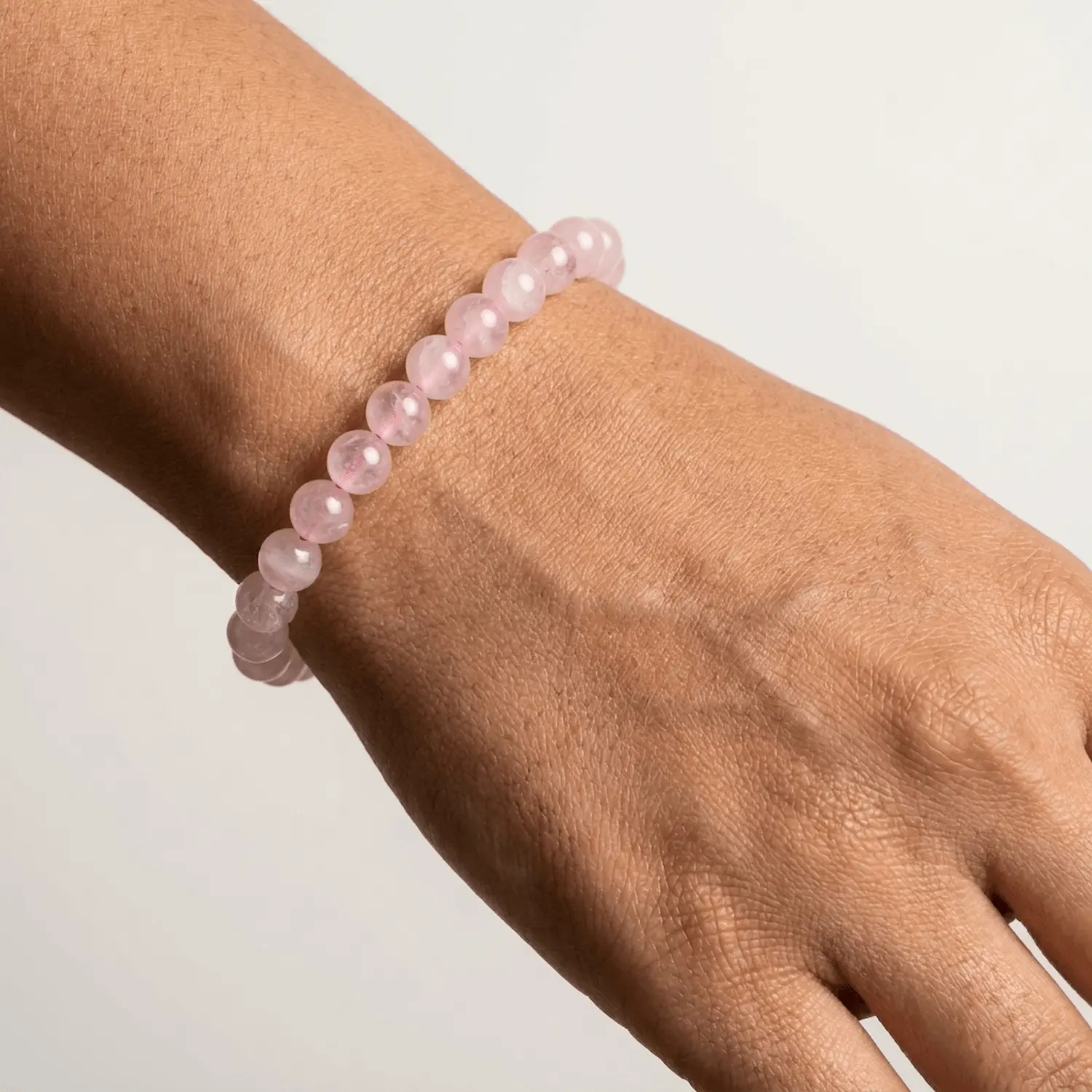 Rose Quartz crystal bracelet with soft pink 8mm gemstone beads worn on wrist in minimal studio lighting