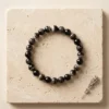 Suleimani Black Hakik crystal bracelet 8mm with polished striped black agate beads displayed on textured neutral background