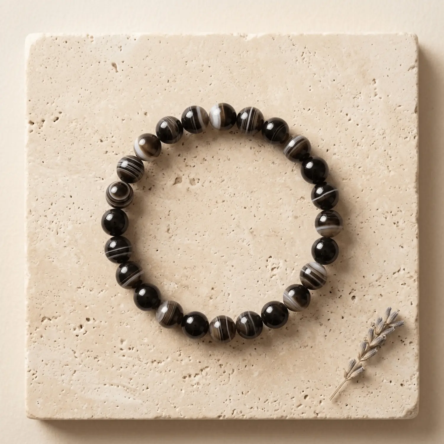 Suleimani Black Hakik crystal bracelet 8mm with polished striped black agate beads displayed on textured neutral background