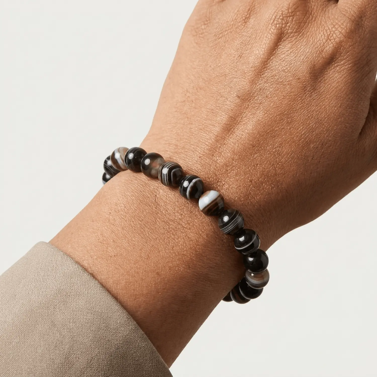 Close up of Suleimani Black Hakik crystal bracelet on wrist featuring natural black and brown striped agate beads in 8mm size