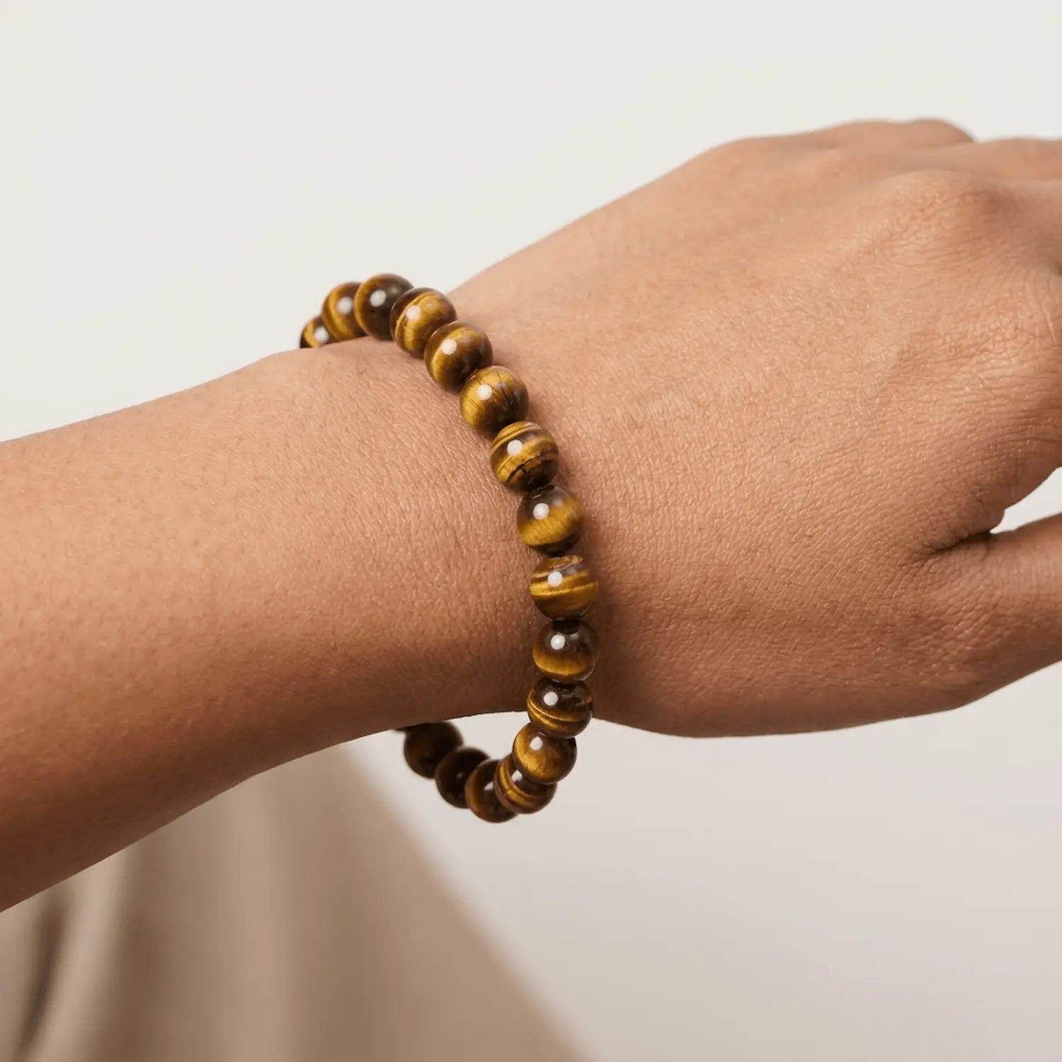 Close up of Tiger’s Eye crystal bracelet 8mm on wrist featuring polished golden brown chatoyant beads in 8mm size