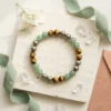 Wealth Combination crystal bracelet styled with Green Aventurine Tiger Eye and Pyrite beads on neutral stone background with crystals