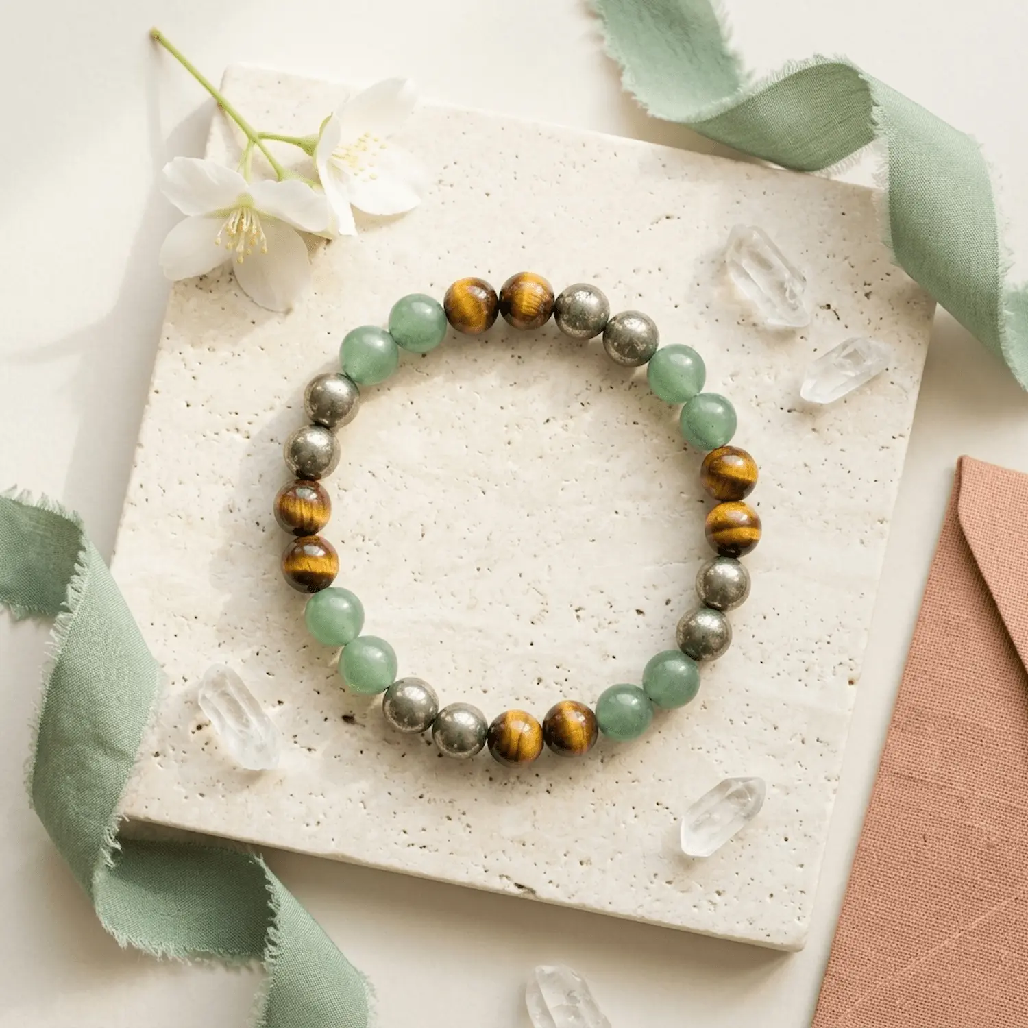 Wealth Combination crystal bracelet styled with Green Aventurine Tiger Eye and Pyrite beads on neutral stone background with crystals
