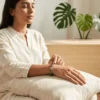 Woman meditating while wearing Wealth Combination crystal bracelet featuring Green Aventurine Tiger Eye and Pyrite gemstones