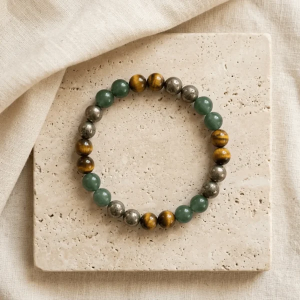 Wealth Combination crystal bracelet with polished Green Aventurine Tiger Eye and Pyrite gemstone beads displayed on textured stone surface