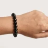 Close-up of 10mm black obsidian crystal bracelet on wrist showing bead shine and size