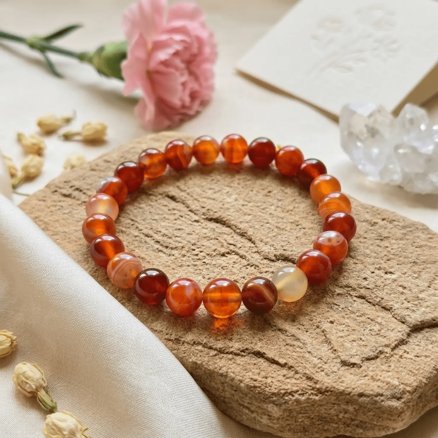 8mm Carnelian crystal bracelet with warm orange polished beads on textured stone surface