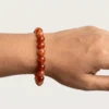 Close-up of 8mm carnelian crystal bracelet on wrist showing bead size and glossy finish