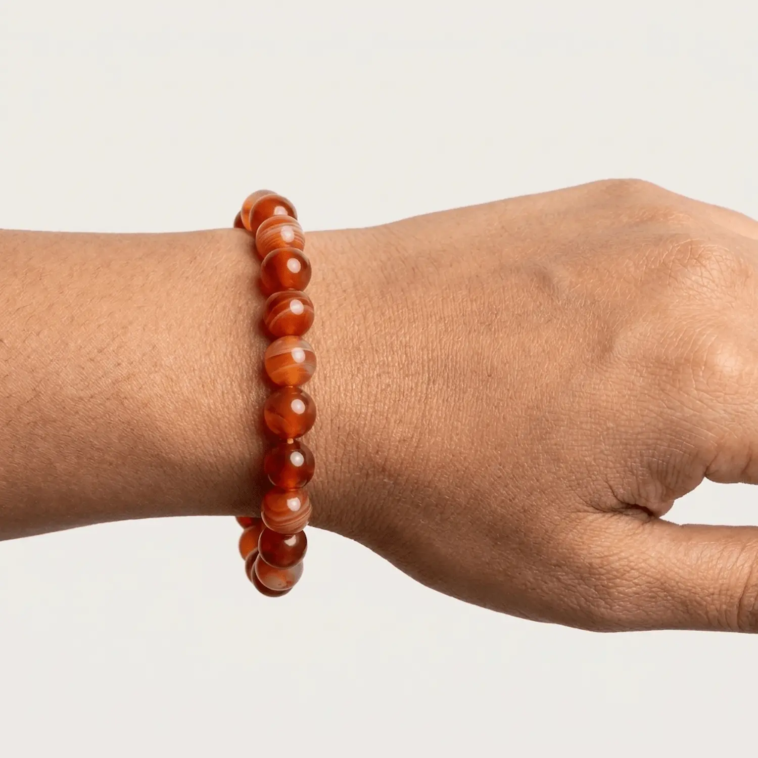 Close-up of 8mm carnelian crystal bracelet on wrist showing bead size and glossy finish