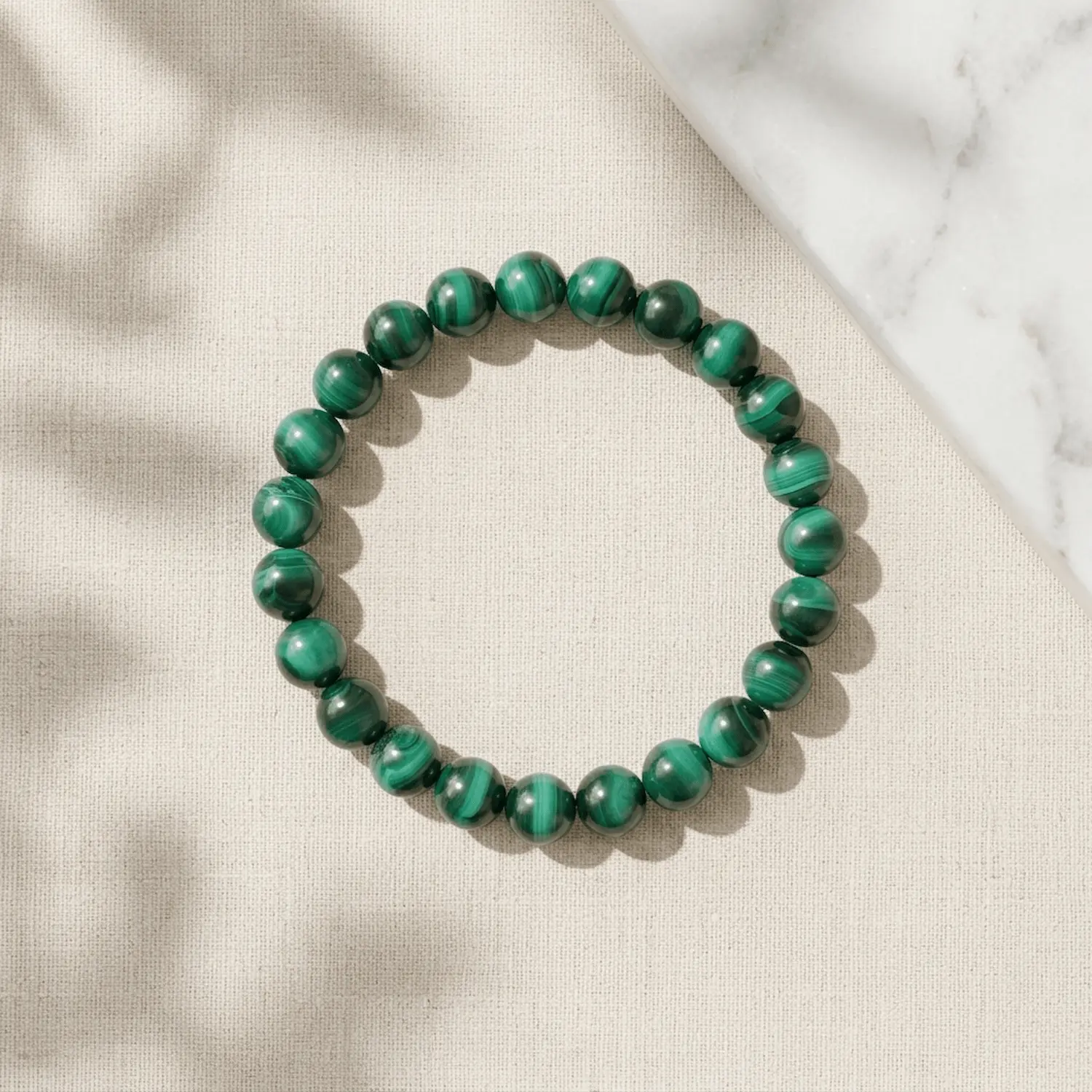 Malachite crystal bracelet 8mm with polished round beads on neutral background