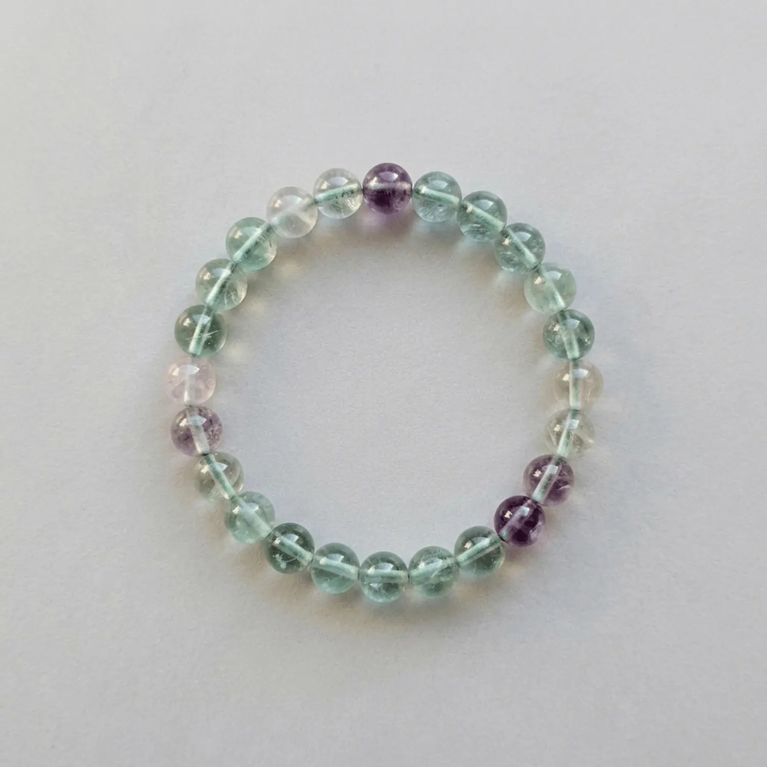 Top view of 8mm multicolored fluorite crystal bracelet showing translucent green and purple bead clarity
