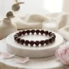 8mm Red garnet crystal bracelet styled on marble surface with soft decor and flowers