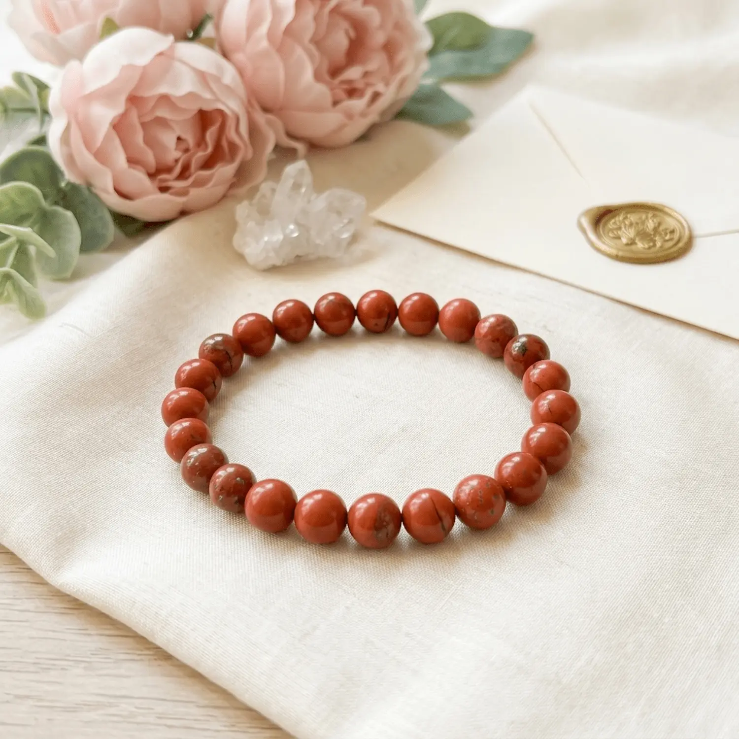 Red Jasper crystal bracelet styled with soft florals and neutral tones highlighting natural beauty and calming aesthetic