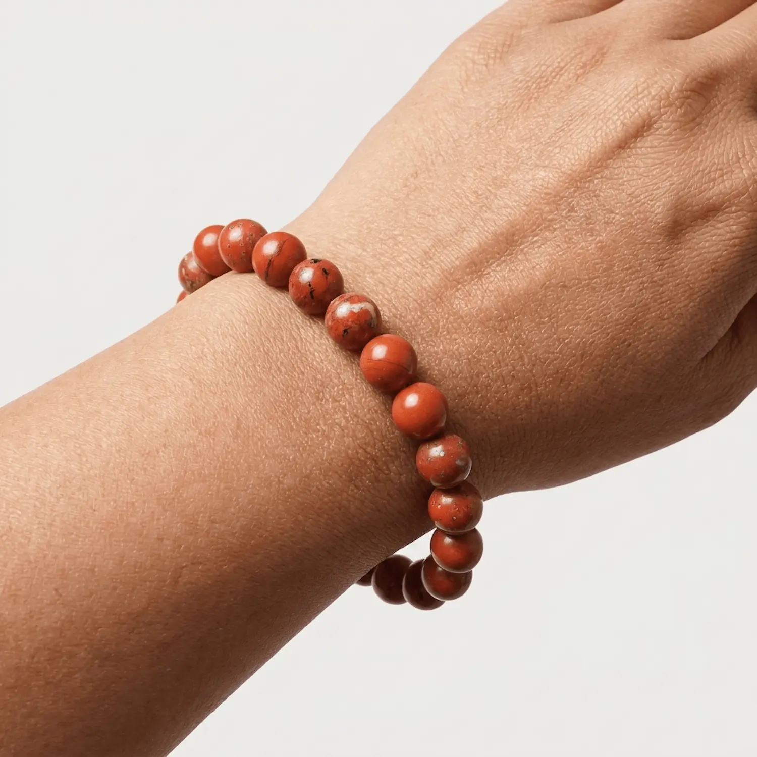 Close up of Red Jasper crystal bracelet on wrist showing smooth 8mm beads, texture and natural variations