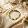 Serpentine crystal bracelet styled with soft fabric, flowers and natural elements highlighting soothing green tones