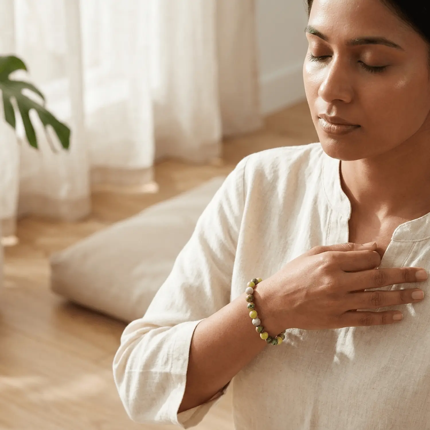 Woman wearing Serpentine crystal bracelet during meditation, promoting emotional healing, balance and inner calm