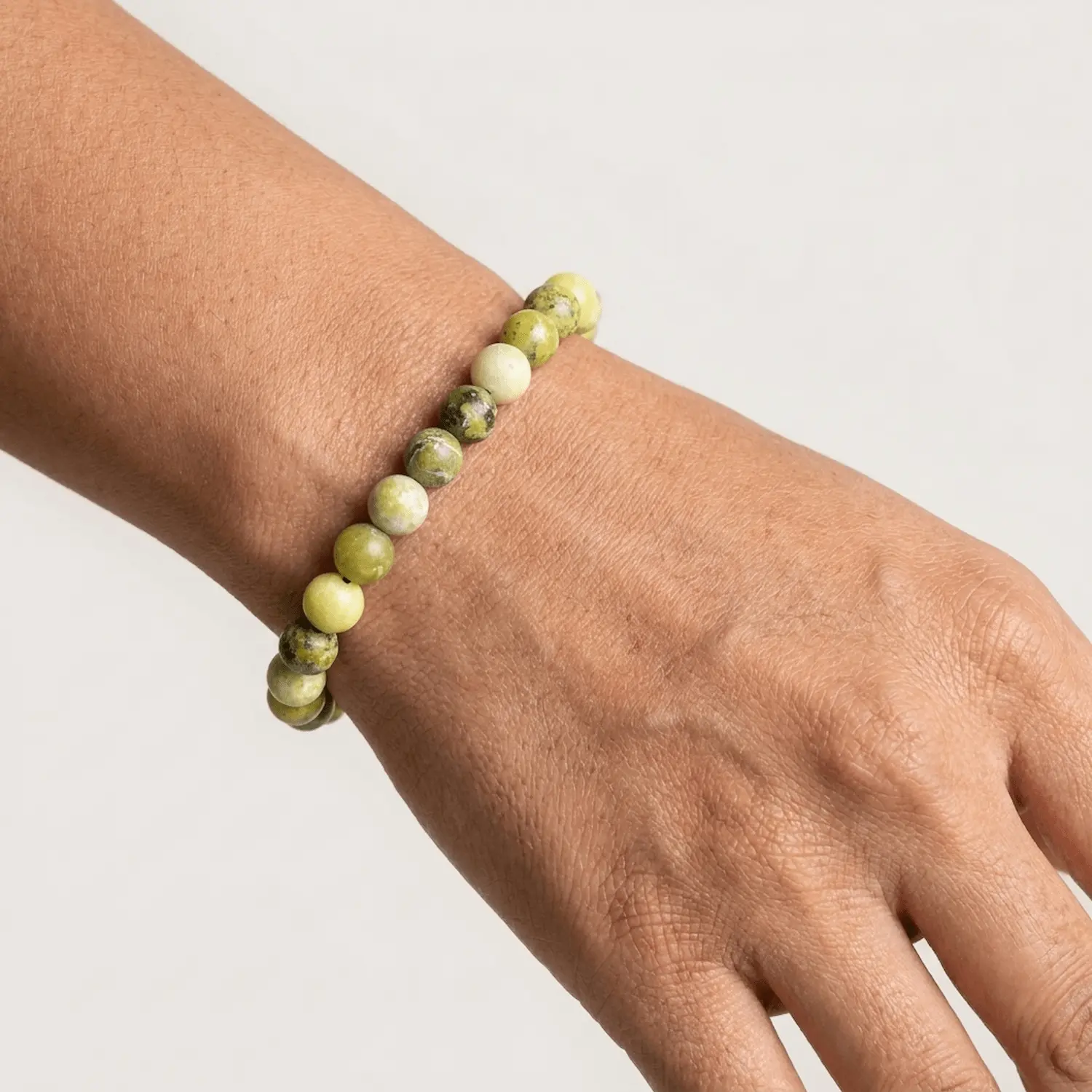 Close up of Serpentine crystal bracelet on wrist showing smooth 8mm beads with natural green variations