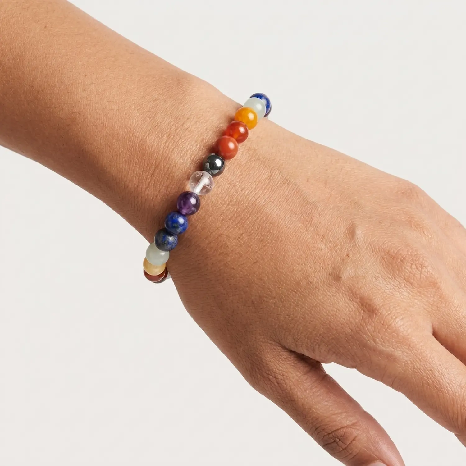 Close-up of seven chakra crystal bracelet on wrist showing bead colors and details