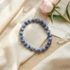 Sodalite crystal bracelet styled with soft fabric, flowers and crystals highlighting natural blue tones and calming energy