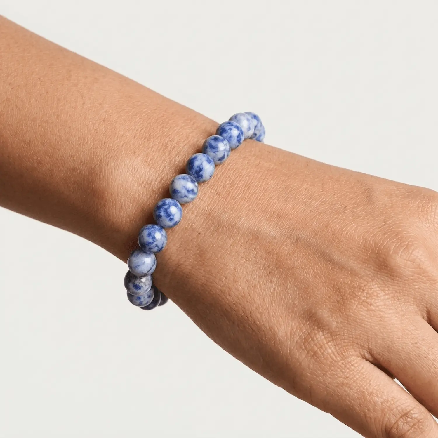 Close up of Sodalite crystal bracelet on wrist showing polished 8mm blue beads with natural white veining