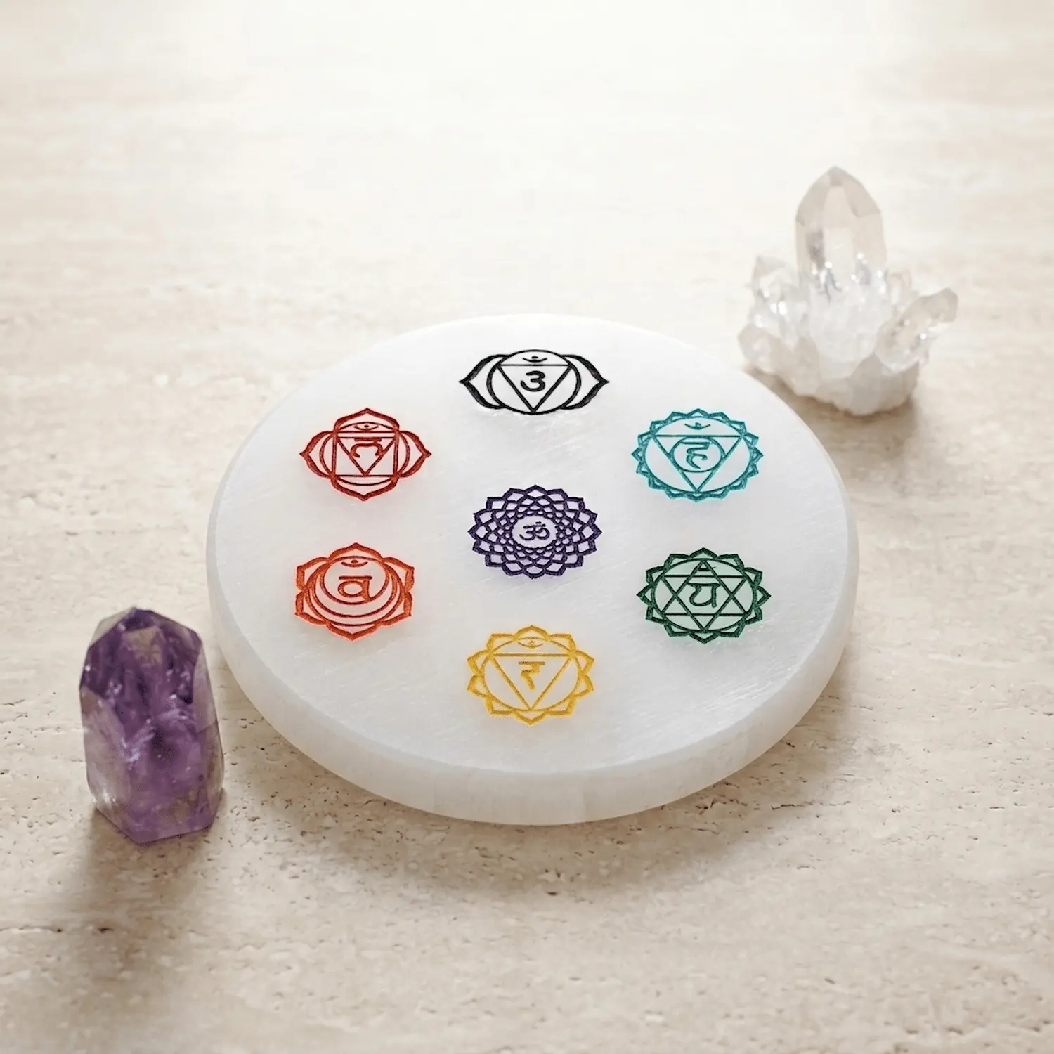 3-inch selenite plate with 7 chakra symbols styled as spiritual home decor